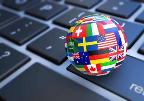International business concept with a computer keyboard and world flags on a globe 3D illustration.